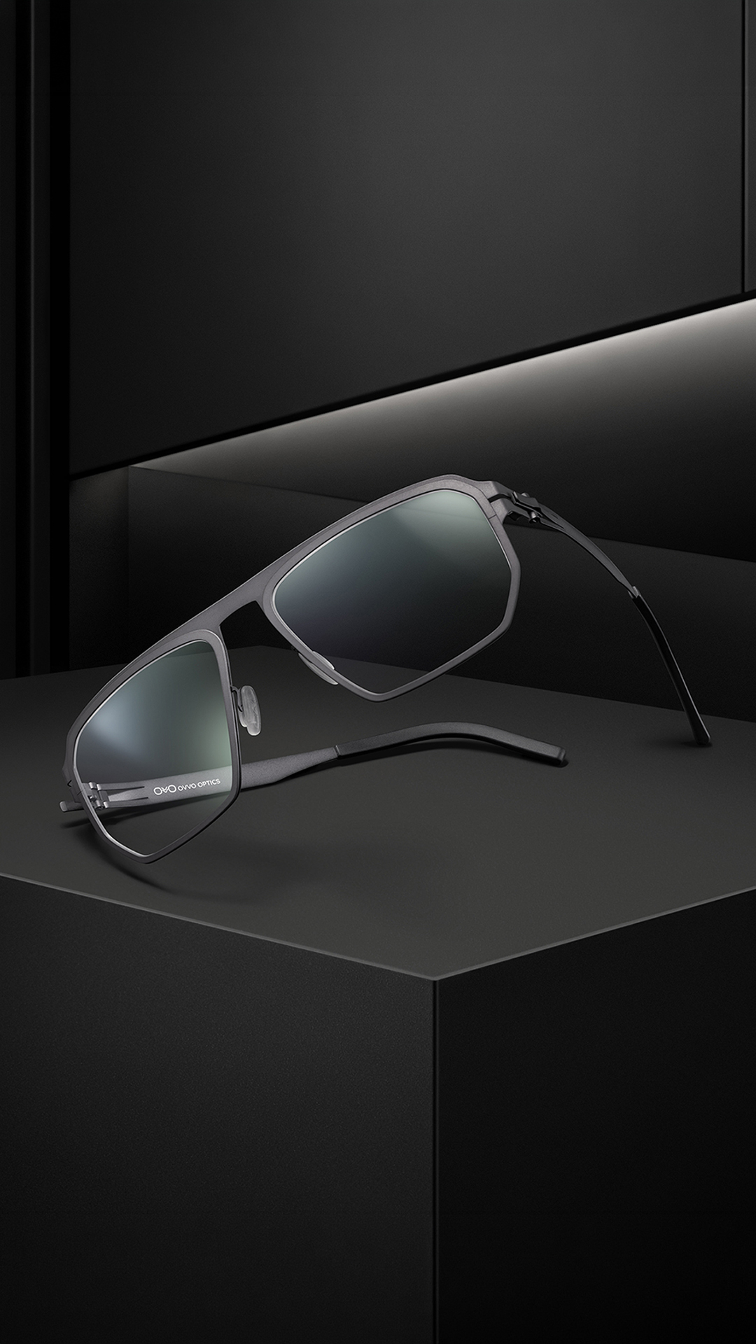 OVVO Optics Ti2 Expanded Atlas titanium sunglasses front view on a dark architectural set