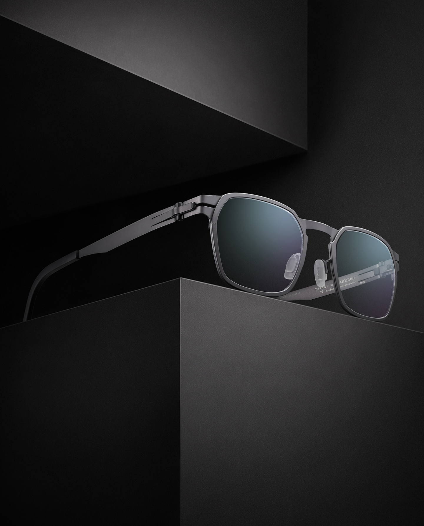 OVVO Optics Ti2 Expanded Typhon sculptural titanium sunglasses displayed on dark geometric blocks