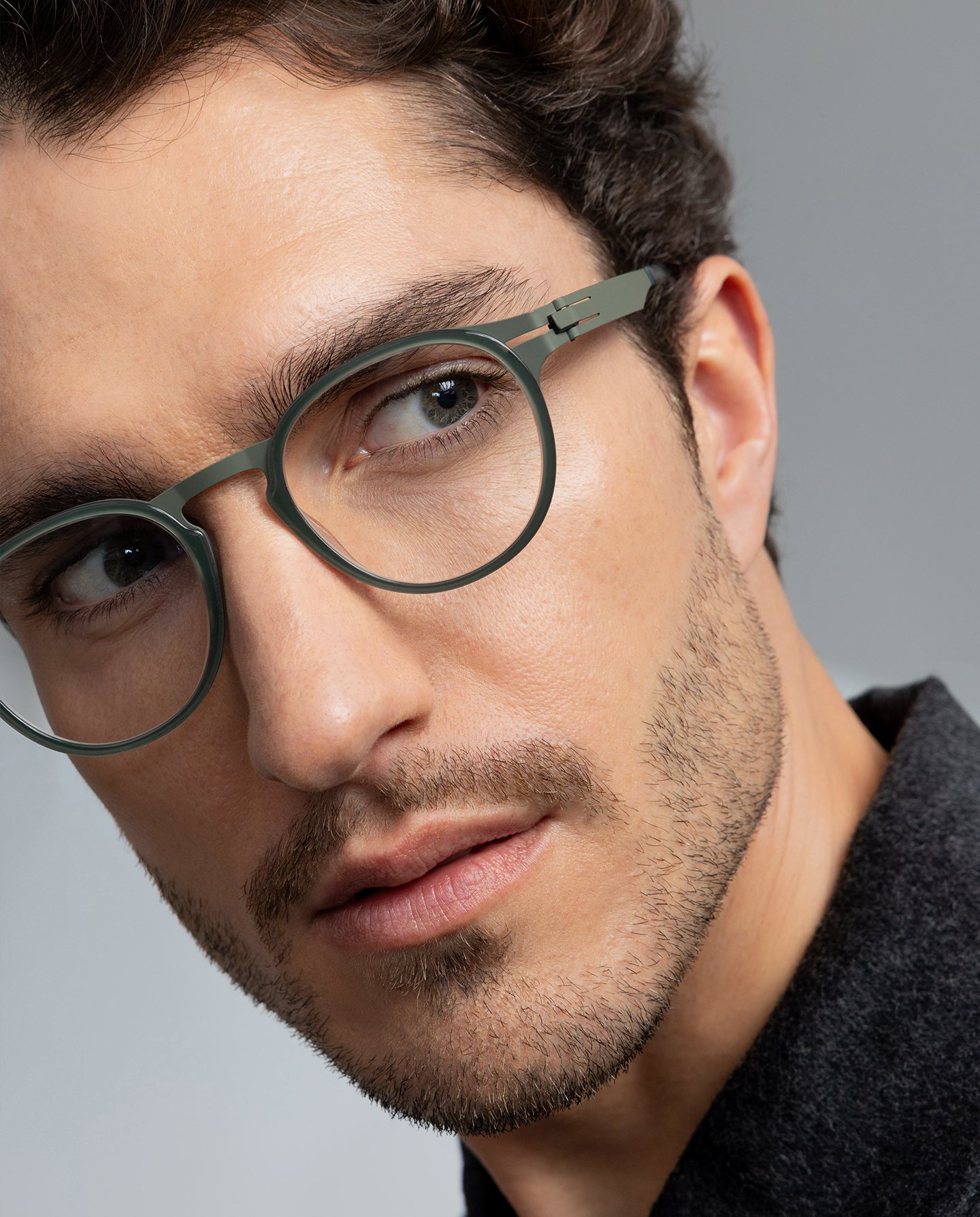 Close-up of a man wearing OVVO Optics DUO Calvin green round eyeglasses with a metal bridge and screwless hinges