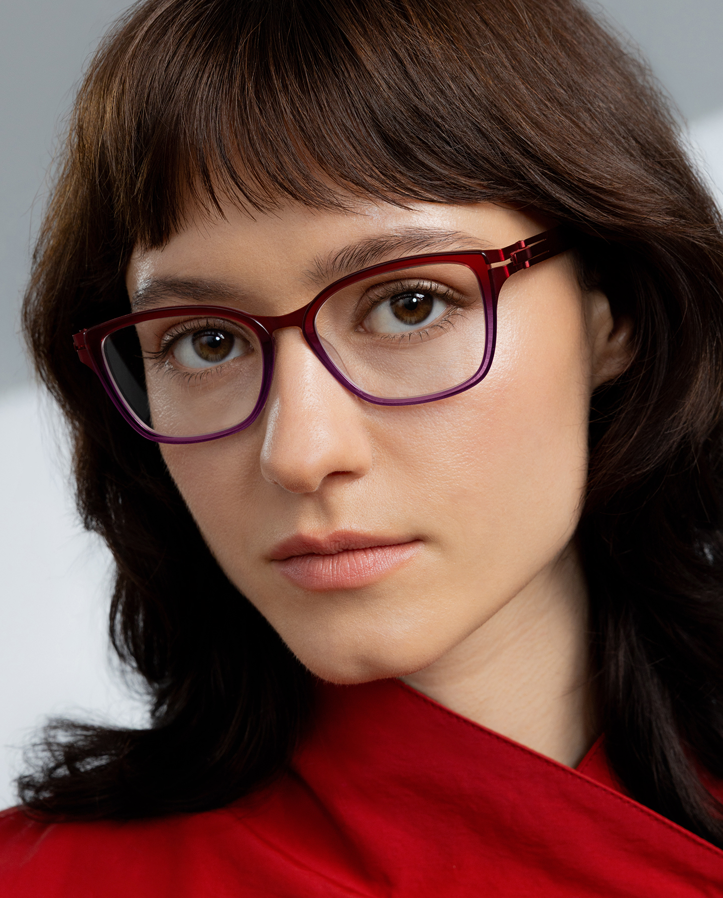 Woman in a red blouse wearing OVVO Optics DUO Marla upswept eyeglasses with a red-to-purple ombré finish